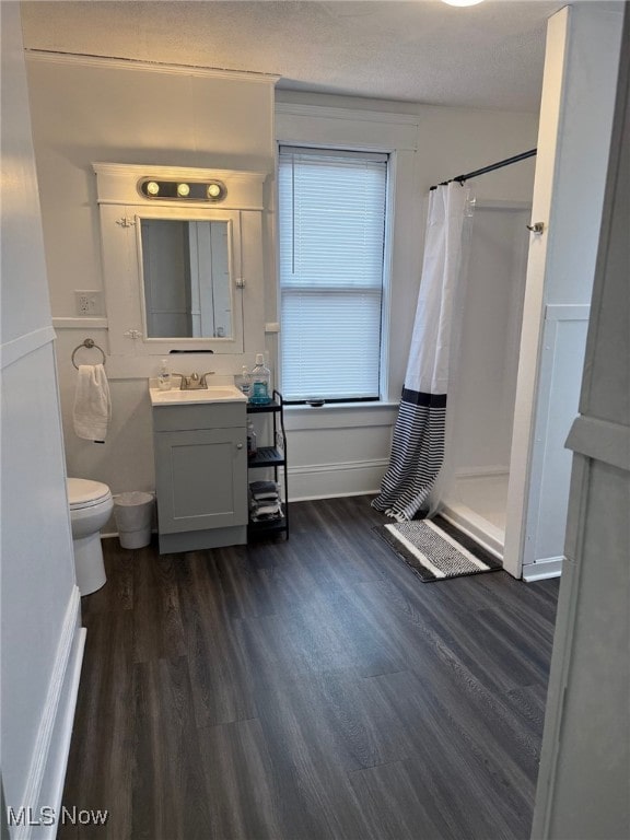full bath with a stall shower, wood finished floors, and toilet