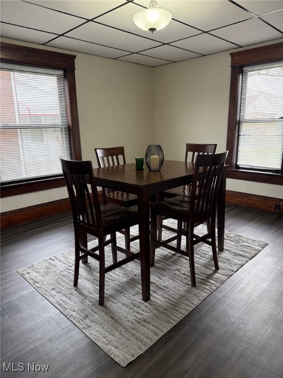 dining space featuring baseboards, a paneled ceiling, and wood finished floors
