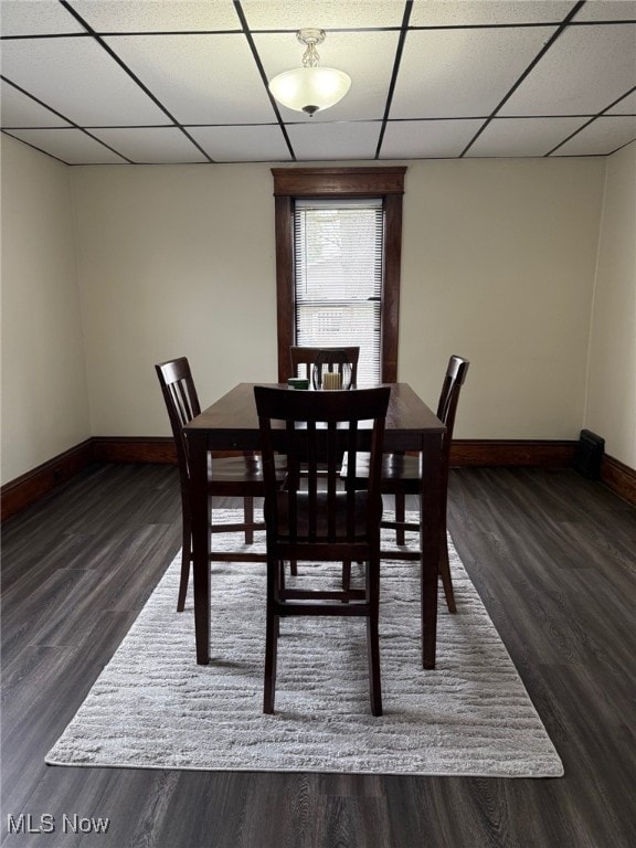 dining area with baseboards, a drop ceiling, and wood finished floors
