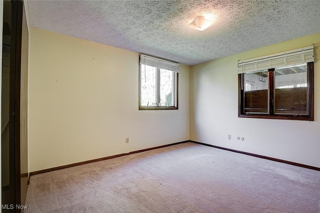 carpeted spare room featuring baseboards and a textured ceiling