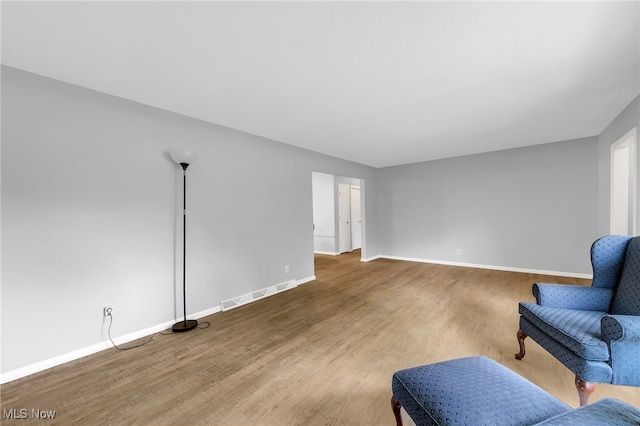 sitting room with baseboards, wood finished floors, and visible vents