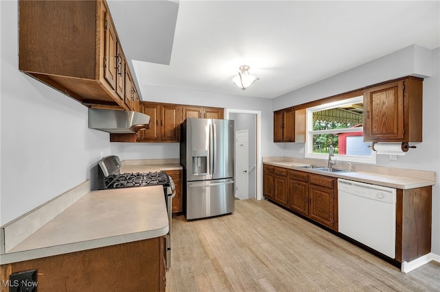 kitchen with light countertops, under cabinet range hood, a sink, light wood finished floors, and stainless steel appliances