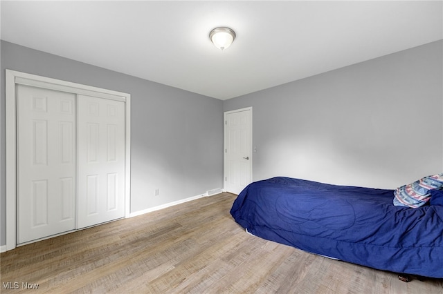 bedroom with baseboards, wood finished floors, and a closet