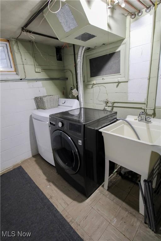 clothes washing area with laundry area, washer and clothes dryer, and concrete block wall