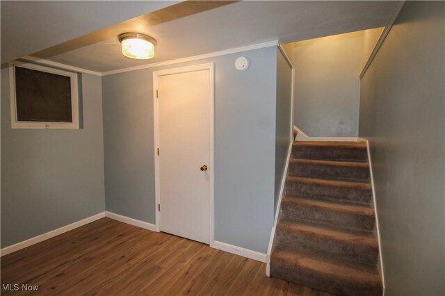 stairway with crown molding, baseboards, and wood finished floors