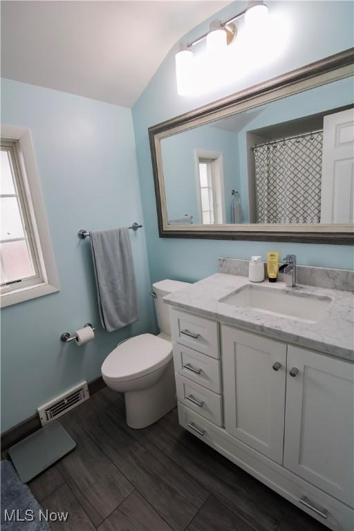 full bathroom with visible vents, vanity, wood finished floors, lofted ceiling, and toilet