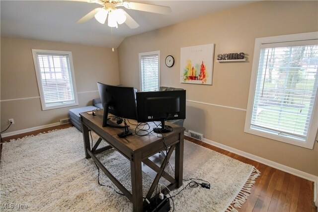 office area with wood finished floors, a wealth of natural light, ceiling fan, and visible vents