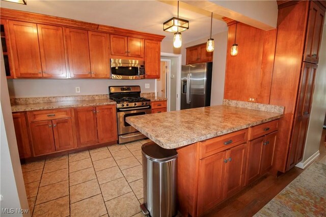 kitchen featuring stainless steel appliances, brown cabinetry, and a peninsula