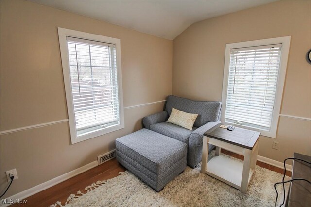 sitting room featuring baseboards, lofted ceiling, wood finished floors, and visible vents