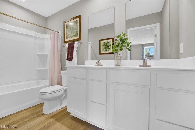 bathroom with double vanity, toilet, wood finished floors, and shower / tub combo with curtain