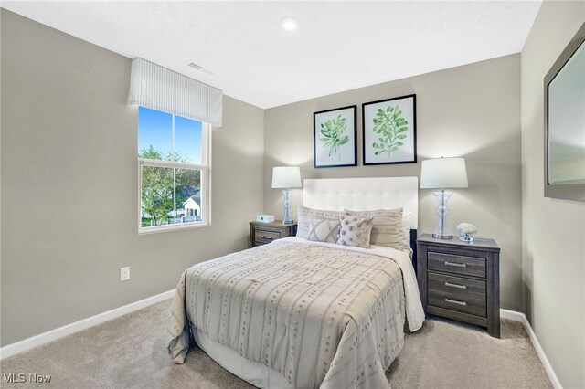 bedroom with baseboards, visible vents, and light carpet