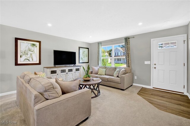 living area featuring baseboards, recessed lighting, and light carpet