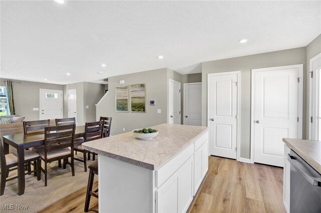 kitchen featuring light wood-style floors, a center island, light countertops, white cabinets, and dishwasher