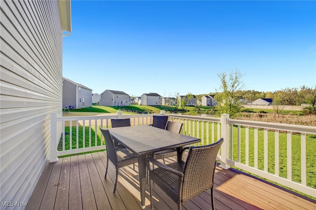 wooden deck featuring outdoor dining area, a yard, and a residential view