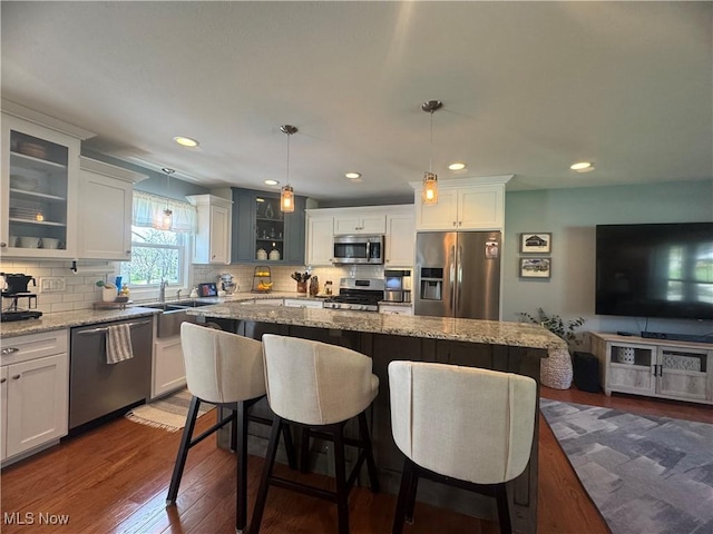 kitchen featuring a sink, appliances with stainless steel finishes, backsplash, and dark wood-style flooring