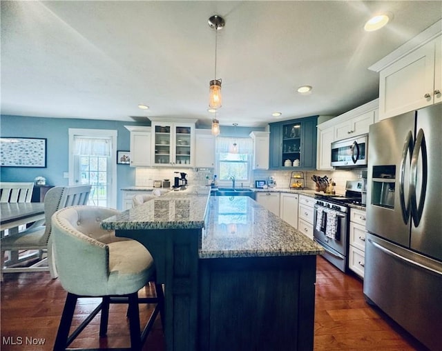 kitchen with appliances with stainless steel finishes, plenty of natural light, glass insert cabinets, and tasteful backsplash
