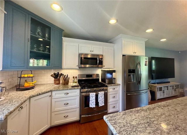 kitchen with decorative backsplash, light stone countertops, white cabinets, glass insert cabinets, and stainless steel appliances