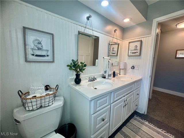 bathroom with double vanity, a sink, baseboards, and toilet
