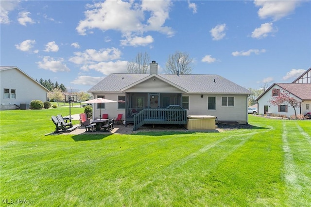 back of property featuring a chimney, a lawn, a sunroom, a patio area, and a hot tub