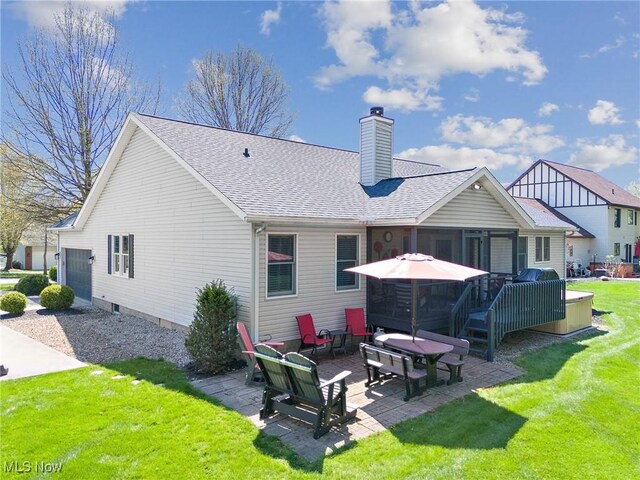 back of house with a lawn, a patio, a chimney, and a shingled roof