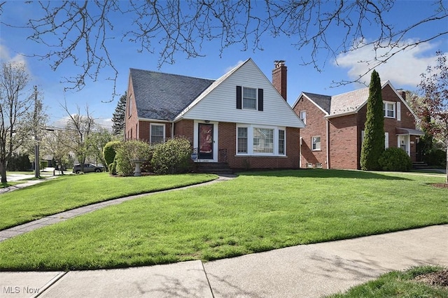 view of front of home featuring brick siding, a front lawn, and a chimney