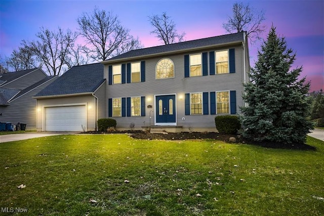 colonial inspired home featuring driveway, a front lawn, and a garage