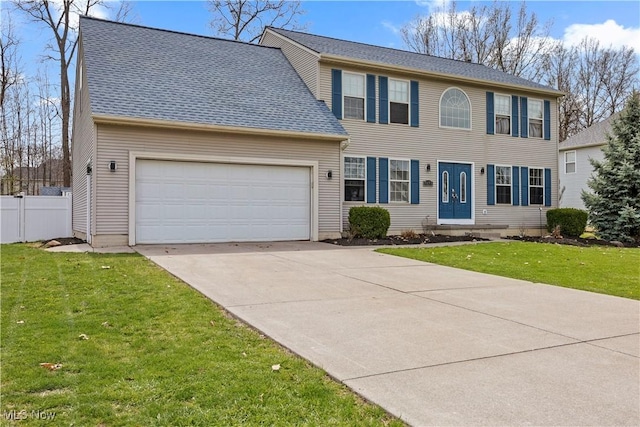 colonial home with a garage, a front lawn, fence, and concrete driveway