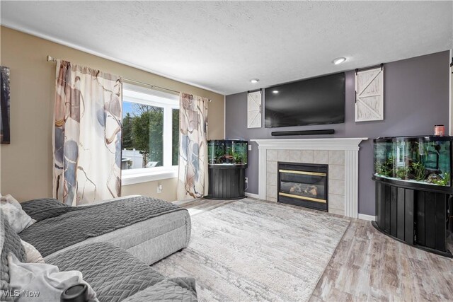 living room with recessed lighting, a textured ceiling, wood finished floors, and a tile fireplace