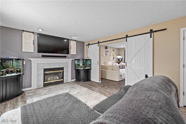 living area with wood finished floors, a fireplace, baseboards, recessed lighting, and a barn door