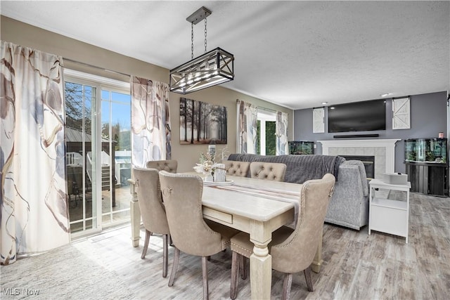 dining area with a textured ceiling, a tiled fireplace, and wood finished floors