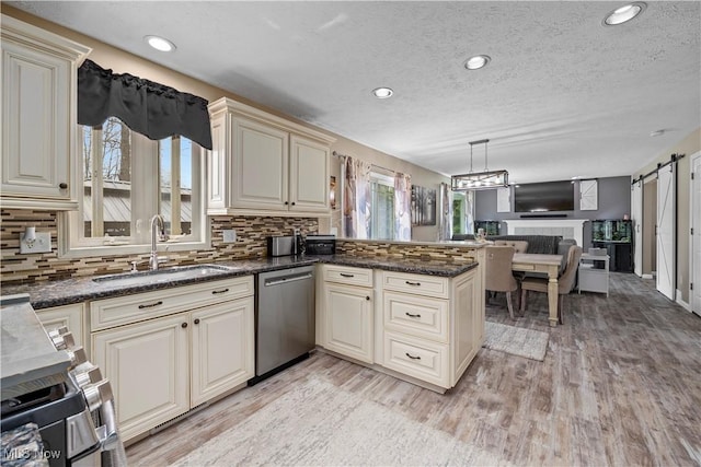 kitchen featuring a sink, cream cabinets, stainless steel dishwasher, and a peninsula
