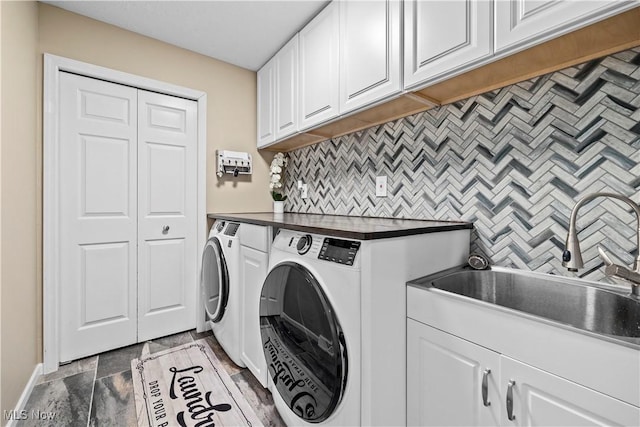 washroom with stone finish flooring, washing machine and dryer, cabinet space, a sink, and baseboards