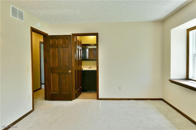 unfurnished bedroom with carpet flooring, baseboards, visible vents, and a sink