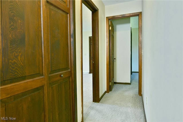 hall featuring baseboards and light carpet