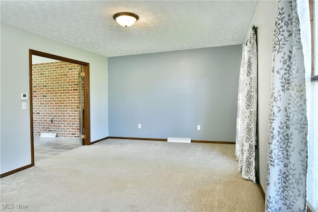 carpeted empty room with baseboards, a textured ceiling, and visible vents