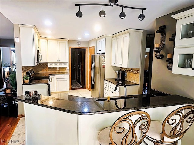 kitchen with a sink, a peninsula, tasteful backsplash, and stainless steel appliances
