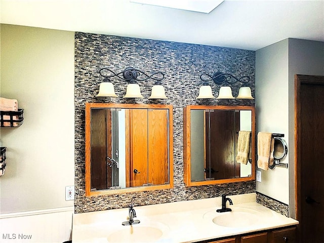 full bathroom featuring double vanity, a sink, and wainscoting