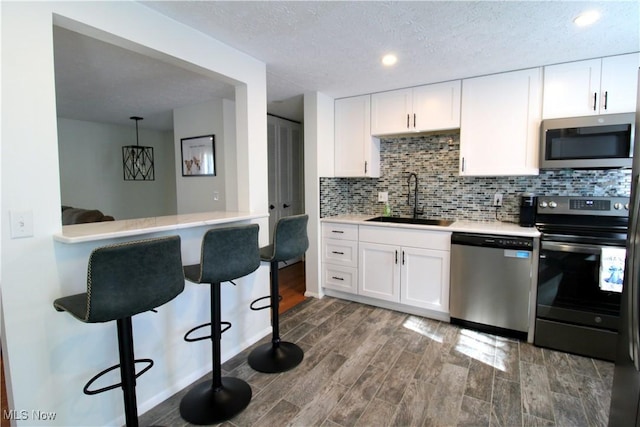 kitchen featuring a sink, light countertops, a kitchen breakfast bar, stainless steel appliances, and tasteful backsplash