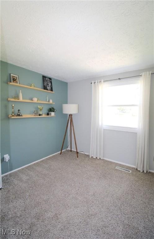 carpeted empty room featuring baseboards and visible vents