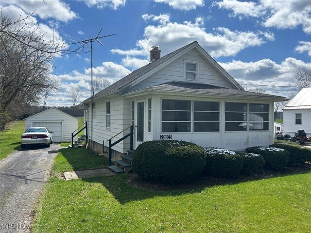 view of front of home featuring driveway, a chimney, a detached garage, a shingled roof, and entry steps