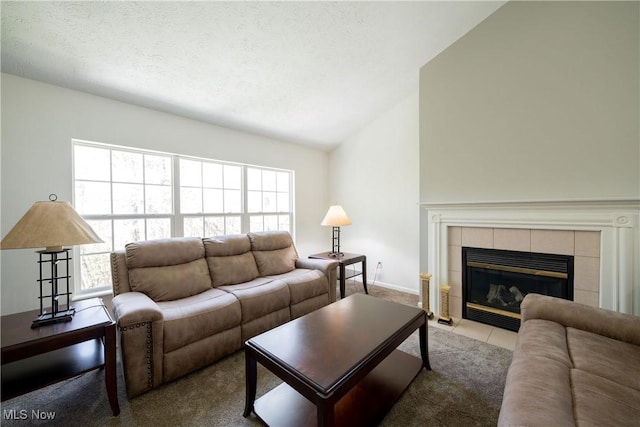 carpeted living room featuring a textured ceiling, vaulted ceiling, a tiled fireplace, and a healthy amount of sunlight