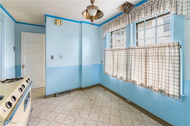 spare room with tile walls, visible vents, and a wainscoted wall