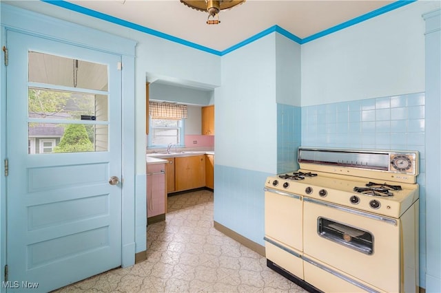 kitchen with light countertops, baseboards, white range with gas cooktop, and light floors