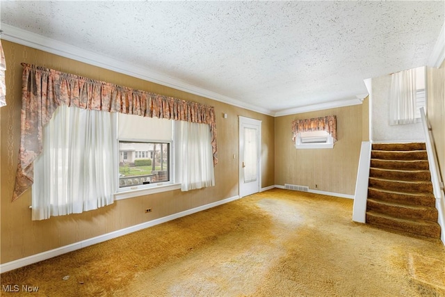 unfurnished living room with a textured ceiling, visible vents, crown molding, stairway, and baseboards