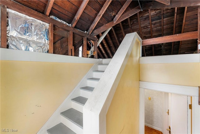stairway featuring lofted ceiling with beams and wooden ceiling