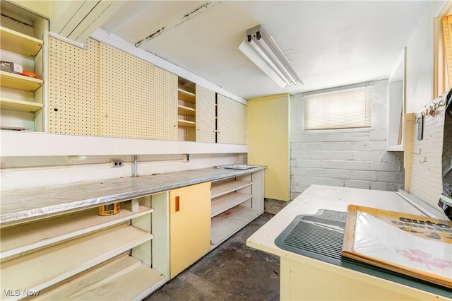 kitchen with light countertops, open shelves, and concrete floors