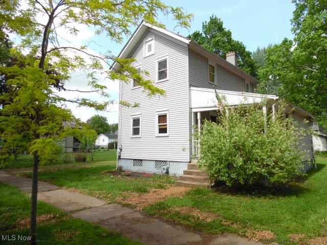 view of home's exterior featuring a lawn and a chimney