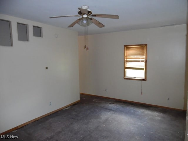 unfurnished room with a ceiling fan, baseboards, and concrete floors