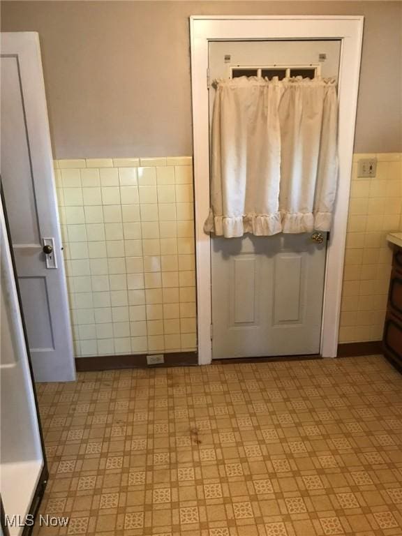 bathroom with tile patterned floors, tile walls, and a wainscoted wall