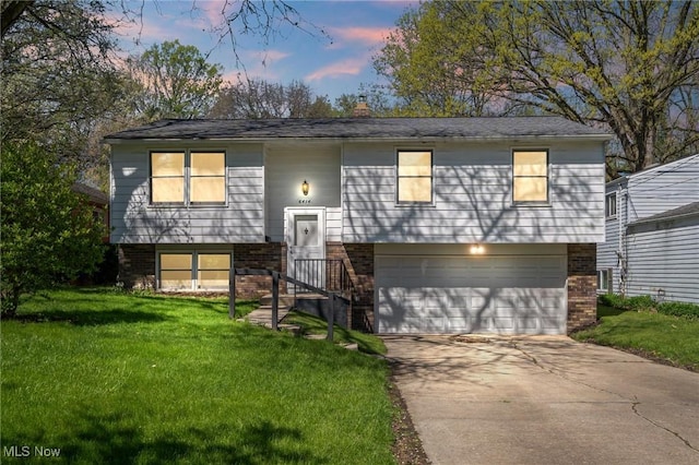 bi-level home featuring a front lawn, a chimney, brick siding, an attached garage, and driveway